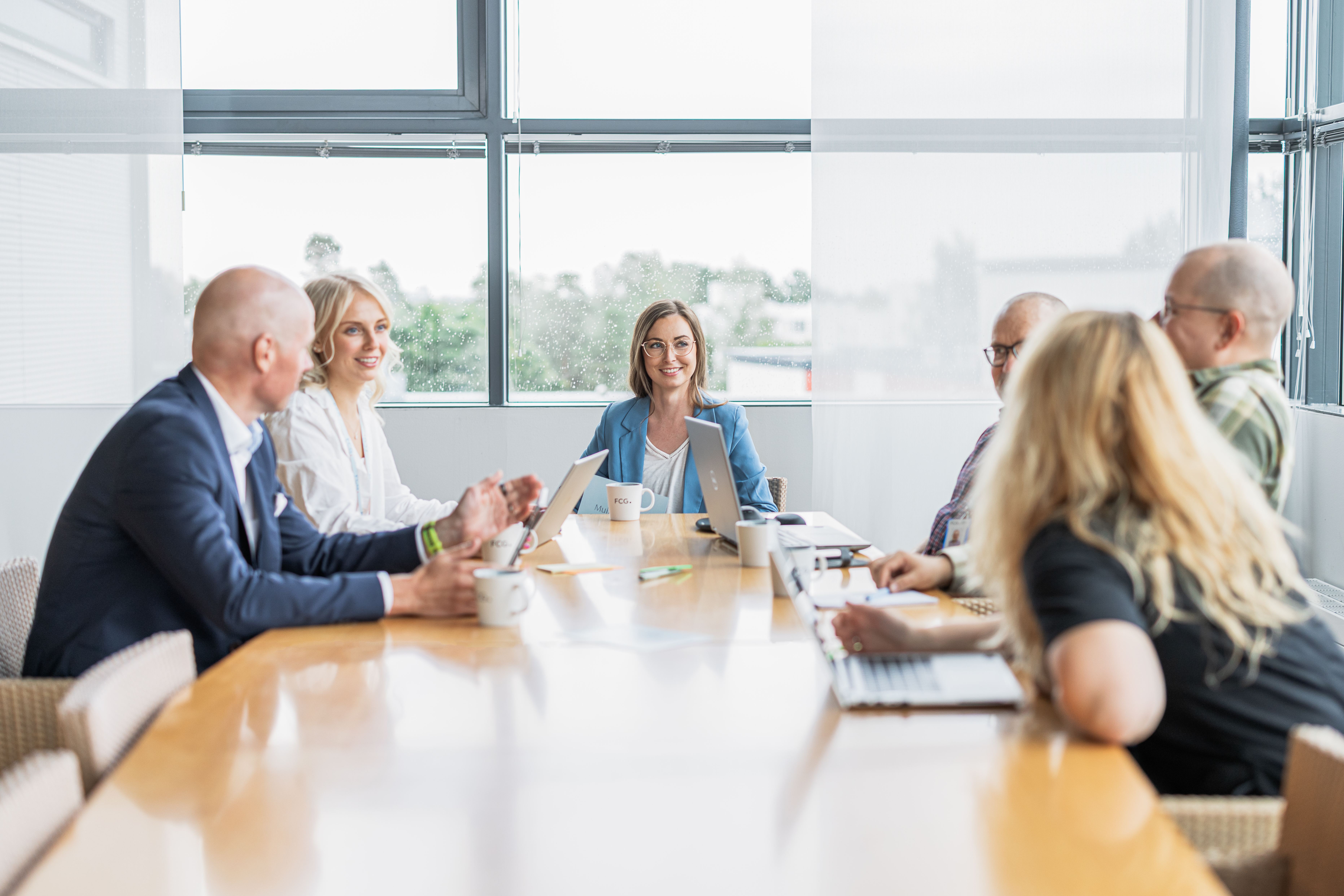 four employees sitting by a conference table and smiling